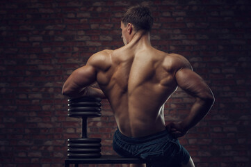 Fototapeta na wymiar Bodybuilder strong man pumping up back muscles
