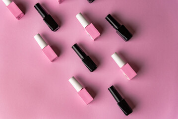 Set of vials with colorful nail lacquer on pink background