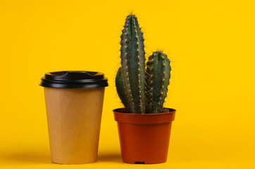 Cactus in pot and coffee cup on a yellow studio background. Minimalism