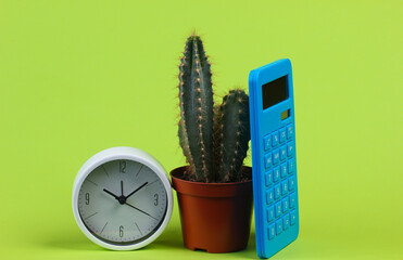 Cactus in pot with calculator, clock on green studio background. Minimalism