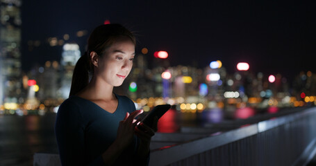 Woman looks at smart phone in city at night