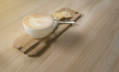 Cup of latte and cookies on wooden tray in cafe.Latte art coffee and dessert.Coffee and tasty cookies on a  wooden table.