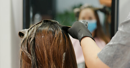 Fototapeta premium Woman undergo hair treatment at beauty salon, dye color on hair