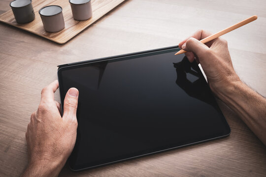 Tablette tenue en main par un homme qui dessine avec un stylet sur un projet artistique, de bureautique ou industriel