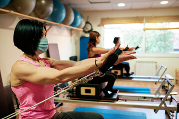 group of mature women doing excercise, Pilates and Yoga with social distancing and face mask