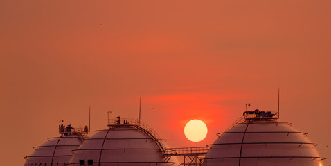Industrial gas storage tank on orange sunset sky. LNG or liquefied natural gas storage tank....