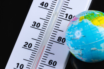 Climate control. Global warming. Weather thermometer with globe on black background.