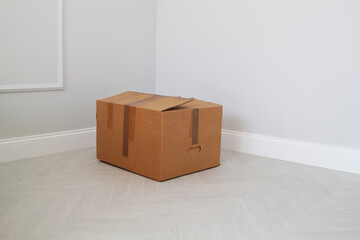 shabby cardboard box in the corner in an empty new room