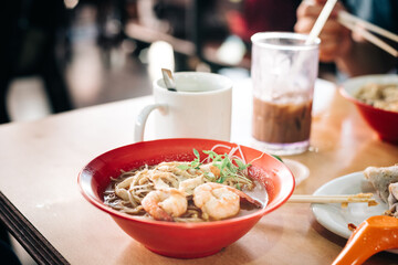 prawn noodles on table with drinks in the background