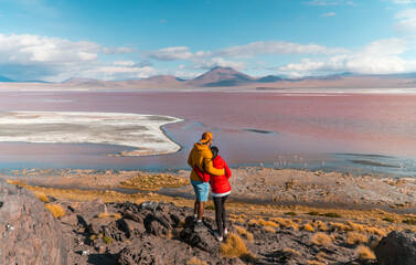 Tourist couple, Red Lake mountain landscape, Bolivia. Tourists in love with Beautiful colored water, mountains background, unique scenic view. Flamingos in the lake. Uyuni, Salar de Uyuni, S America © Jam Travels