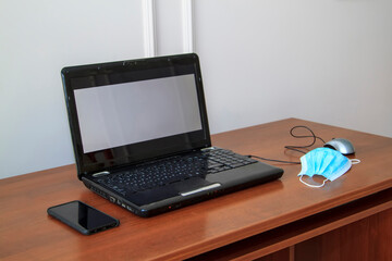 workplace at home for remote work in new normal with laptop and face mask - solution against spread of coronavirus for employees quarantined during COVID-19 outbreak.