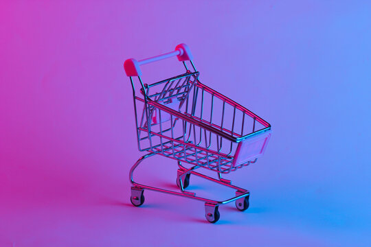 Shopping trolley in trendy neon light. Gradient pink-blue glow. Concept art. Minimalism