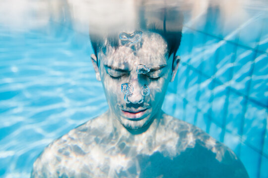 Man underwater with esey closed being calm and thoughtful