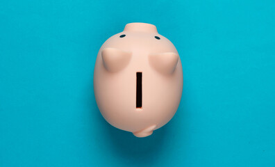 Piggy bank on blue background. Minimalistic studio shot. Overhead view. Flat lay.