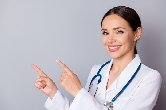 Closeup photo of attractive family doc experienced professional direct fingers empty space remind patients vaccination time wear medical uniform lab coat stethoscope isolated grey background