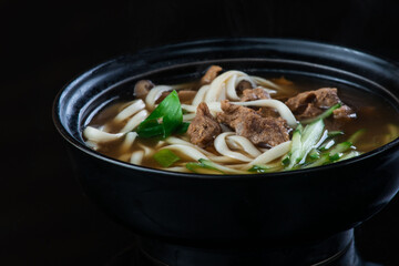 Japanese Soup With Chicken, Egg, Simeji Mushrooms and Eggplant On a Dark Background in a black plate. close up