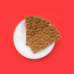 Healthy snack from wholegrain rye Crispbread Crackers on the red background. Top view.  Rye crispbreads  on colored background. Crispbreads  on  the bowl. Minimalism concept.