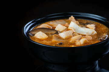 Japanese Soup With Chicken, Egg, Simeji Mushrooms and Eggplant On a Dark Background in a black plate. close up