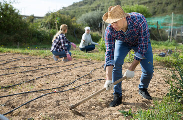 Friendly family of farmers working on garden beds