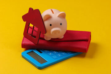 Buying a home. Piggy bank, house figurine, calculator, wallet on a yellow background.