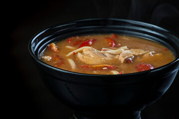 Japanese Soup With Chicken, Egg, Simeji Mushrooms and Eggplant On a Dark Background in a black plate. close up