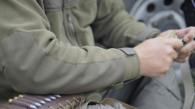 A hunter or huntsman on a halt charges a rifle. Hands of a man insert cartridges into a rifle store, close-up