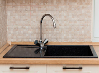 Mixer with black granite sink in the kitchen. Stylish design of the kitchen worktop. Luxurious...