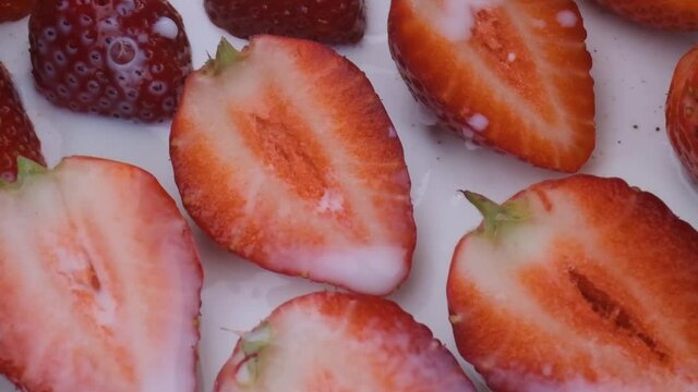 beautiful ripe strawberry in milk close-up,sliced strawberry rotating,fruit macroshooting,healthy food and diet concept,source of vitamins,isolated half strawberry on white background rotates