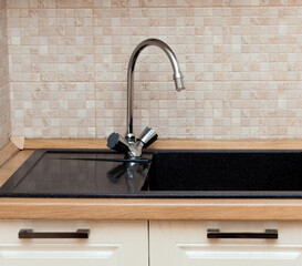 Mixer with black granite sink in the kitchen. Stylish design of the kitchen worktop. Luxurious...