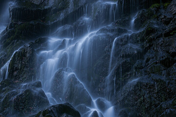 Mystery waterfall cascading over rocks in dark setting