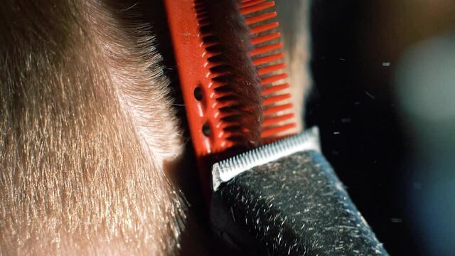 Close-up barber gently clipping head hair with clipper. Hairdresser using a clipper comb. Slow motion. 