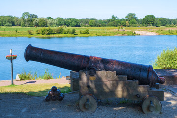Blick auf die Maas bei Arcen/Niederlande mit einer historischen Kanone im Vordergrund