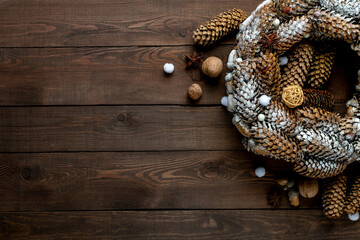 Christmas holiday wreath of cones on a wooden table, top view. Copy space. New Year card.