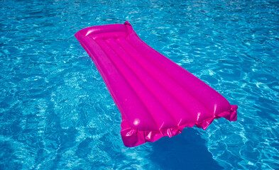 Pink air mattress on a swimming pool, tropical background concept.