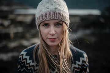 Portrait of a young woman posing in handmade knitted hat. Natural blonde haired woman looking to a camera