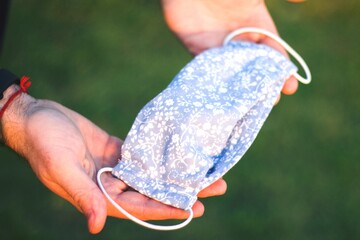 Protective cotton female handmade face mask in male hands, protection from viruses