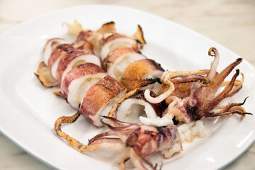 Grilled squid on white plate usually serve with spicy seafood sauce.