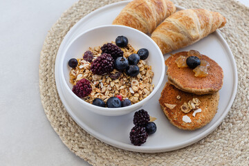 Healthy breakfast concept. Granola with berries, croissants and pancakes