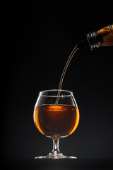 Whisky pouring into a glass on black background