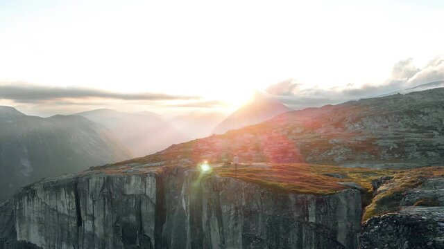 Junger Mann l&auml;uft auf Gipfel im Sonnenuntergang in Norwegen, Abendwanderung in Norwegen, Drohnenshot