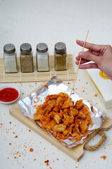 Girl tasting chicken chop on aluminum foil. Street food. Delicious Snack idea.