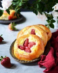 Homemade buns with cottage cheese and strawberries (cheesecakes) in a dish on a gray background, Russian cuisine
