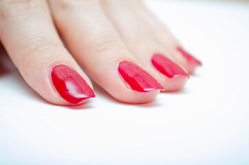 Manicure at home. DIY manicure. The girl paints herself nails in red, burgundy. Glossy nail polish. Macro in macro. Brush is applying varnish on the nail in a strong large zoom on a white background