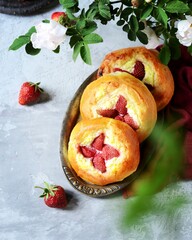 Naklejka na ściany i meble Homemade buns with cottage cheese and strawberries (cheesecakes) in a dish on a gray background, Russian cuisine