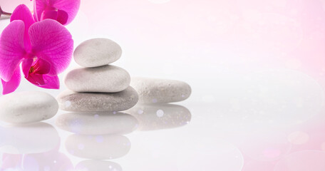 Wellness, relax, massage and wellbeing concept. Spa stones and orchid flower over light pink background. Copy space