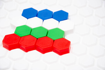 Children's mosaic in macro. Hexagonal puzzle in the form of a honeycomb, element, detail for laying out a picture. Lines of the same colors of details side view, top view on a white background