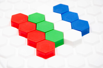 Obraz premium Children's mosaic in macro. Hexagonal puzzle in the form of a honeycomb, element, detail for laying out a picture. Lines of the same colors of details side view, top view on a white background