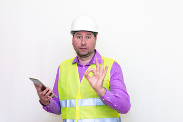 Construction builder wearing helmet yellow protective vest using wireless tablet and showing like or thumbs-up shocked poke up shows to you and victory  gesture isolated on white background.