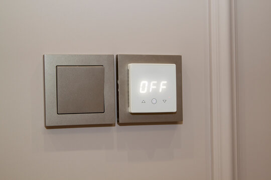 Close up view of electric light switch and sensor for floor heating on an empty wall