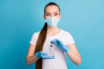 Fototapeta na wymiar Photo of pretty cheerful lady hold hands antiseptic big bottle disinfection safety concept advising sterile hundred protection wear gloves face mask isolated blue color background